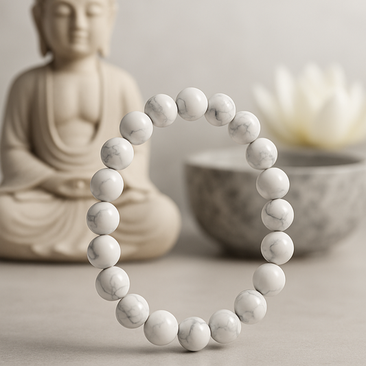 White beaded bracelet on a neutral background with a Buddha statue and bowl.